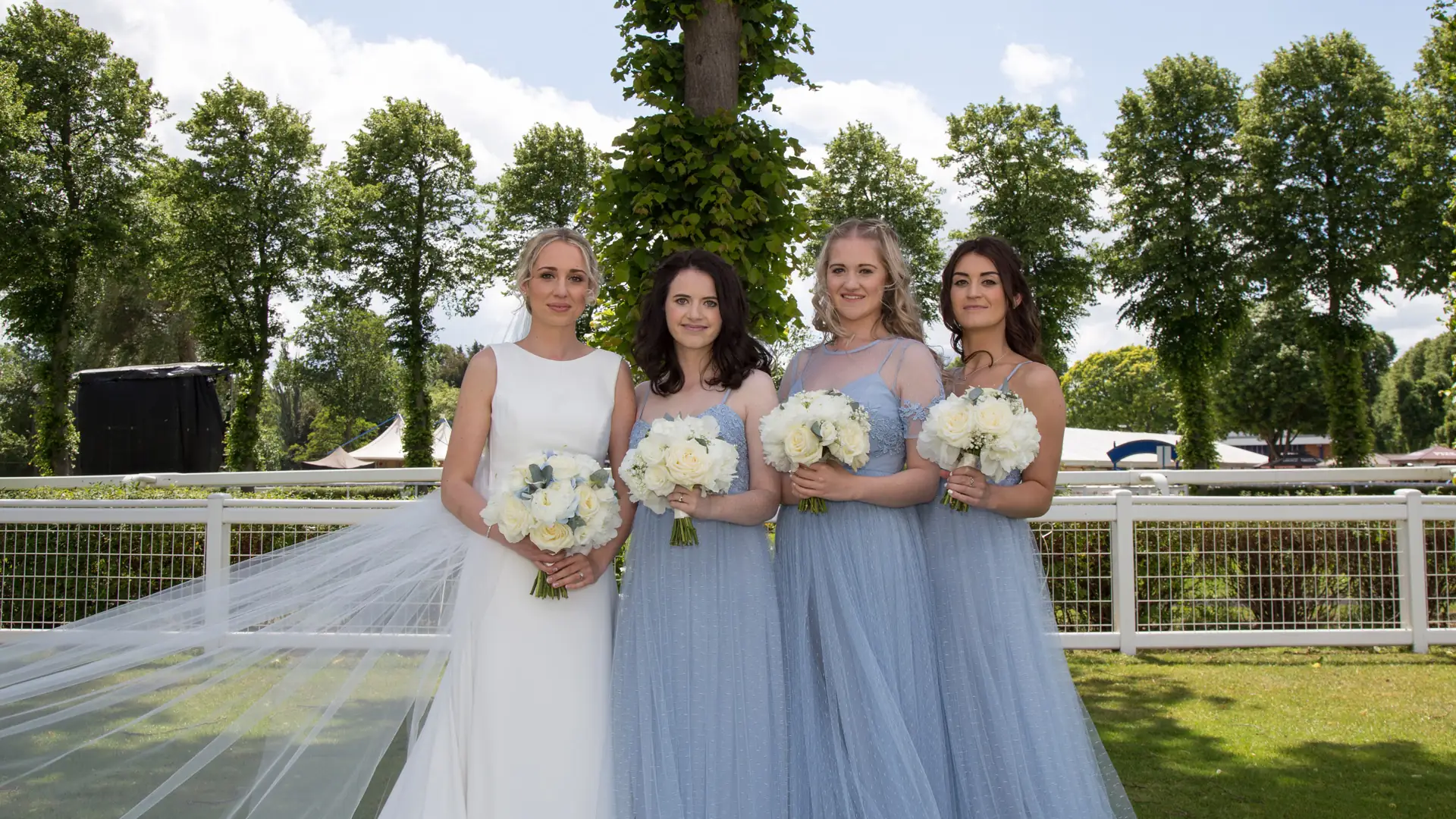 Bride and bridesmaids holding white rose bouquets — wedding hair and makeup for the whole bridal party near Reading